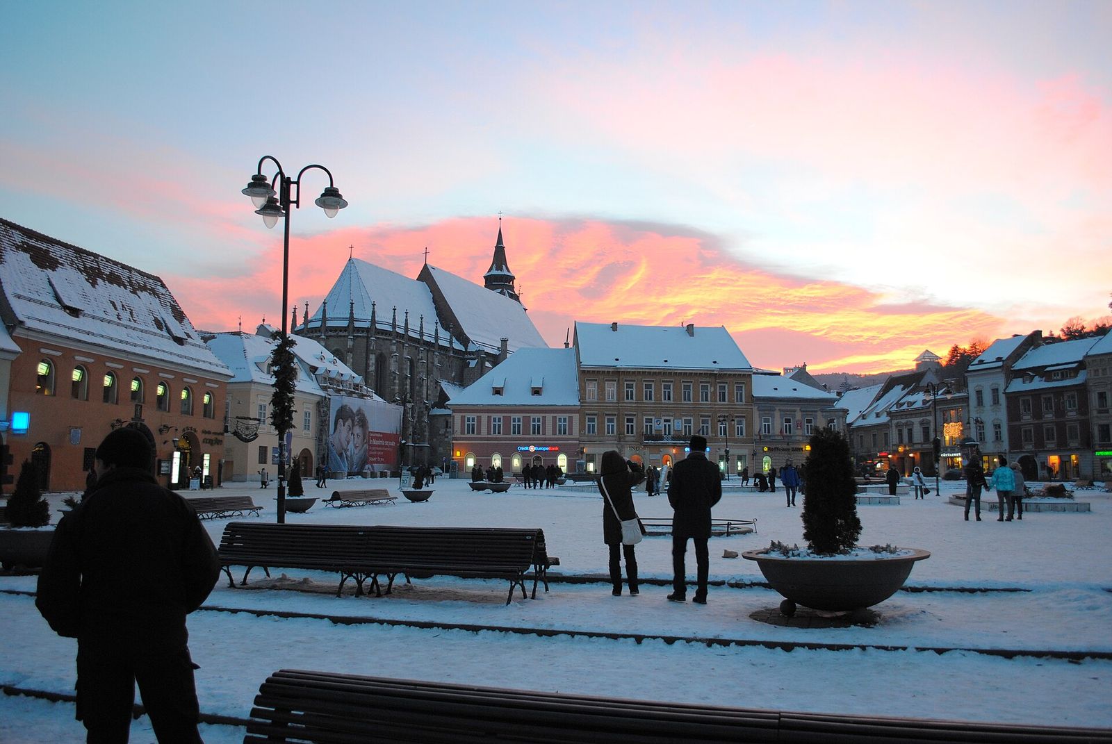 Brașov's snowy Council Square under a pink winter sunset