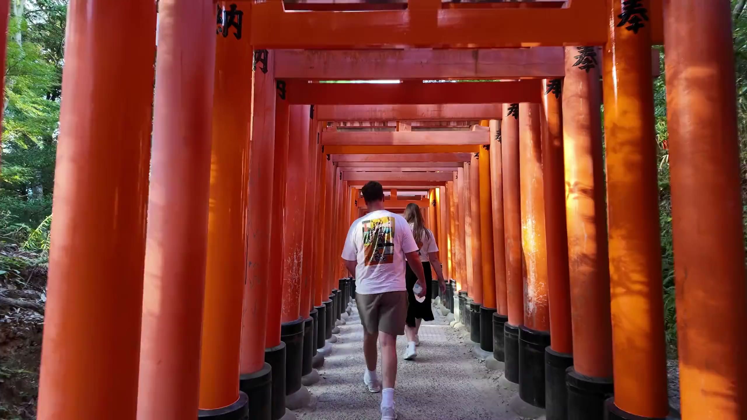 Travellers walking up through the red torii gates of Fushimi Inari