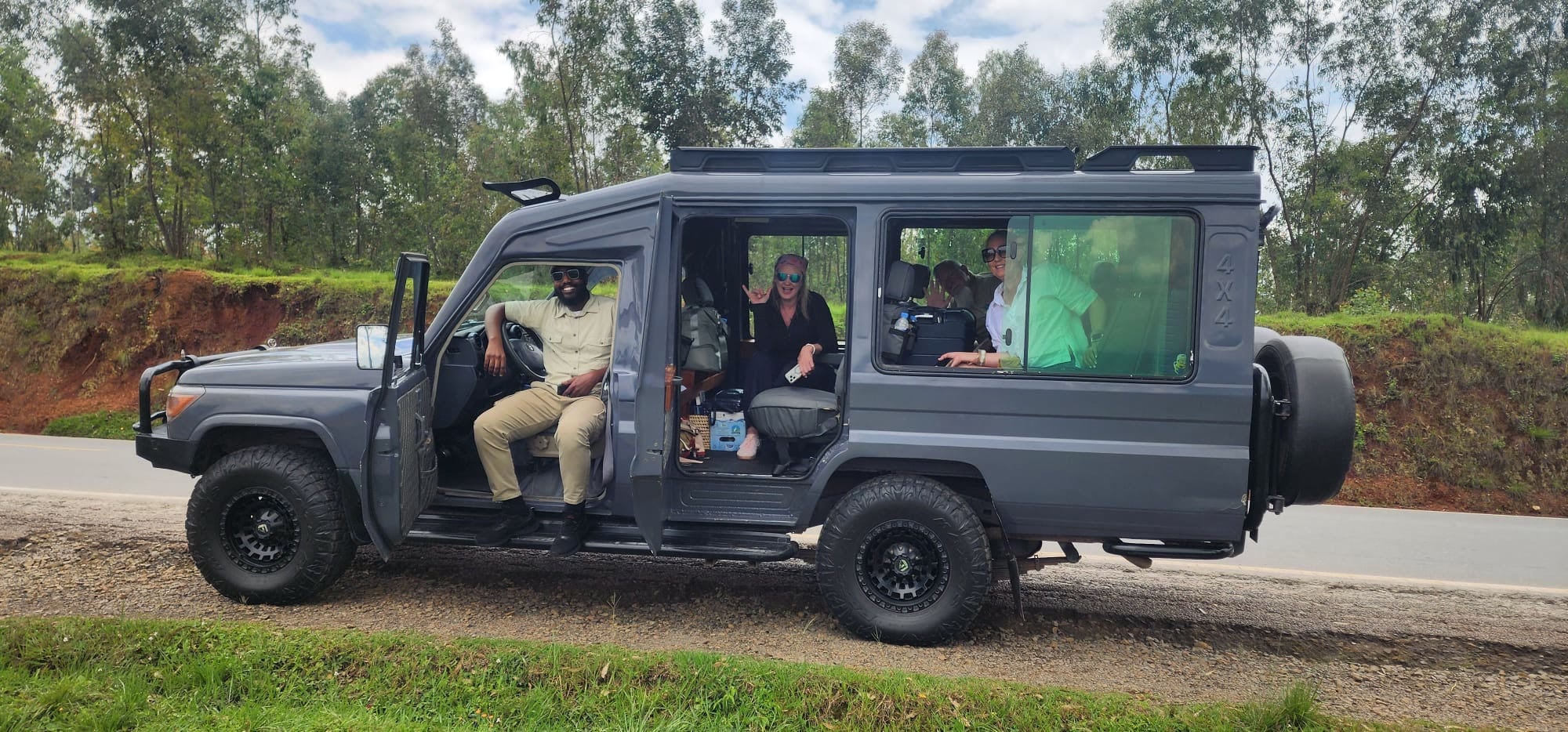 Smiling guests and their guide in a private 4×4 by a green roadside